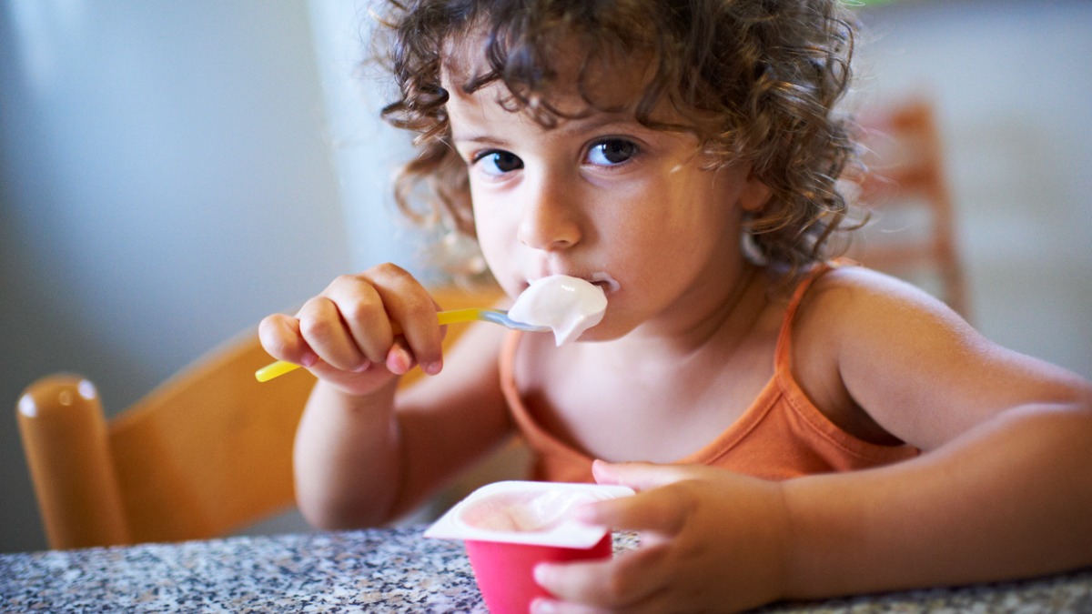 Un enfant mange un yaourt aux fruits